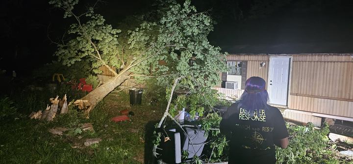 Volunteers work under lights to clear a downed tree at night