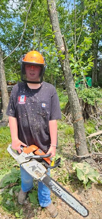 A volunteer in a hard hat holds a chainsaw in Springfield, Ohio